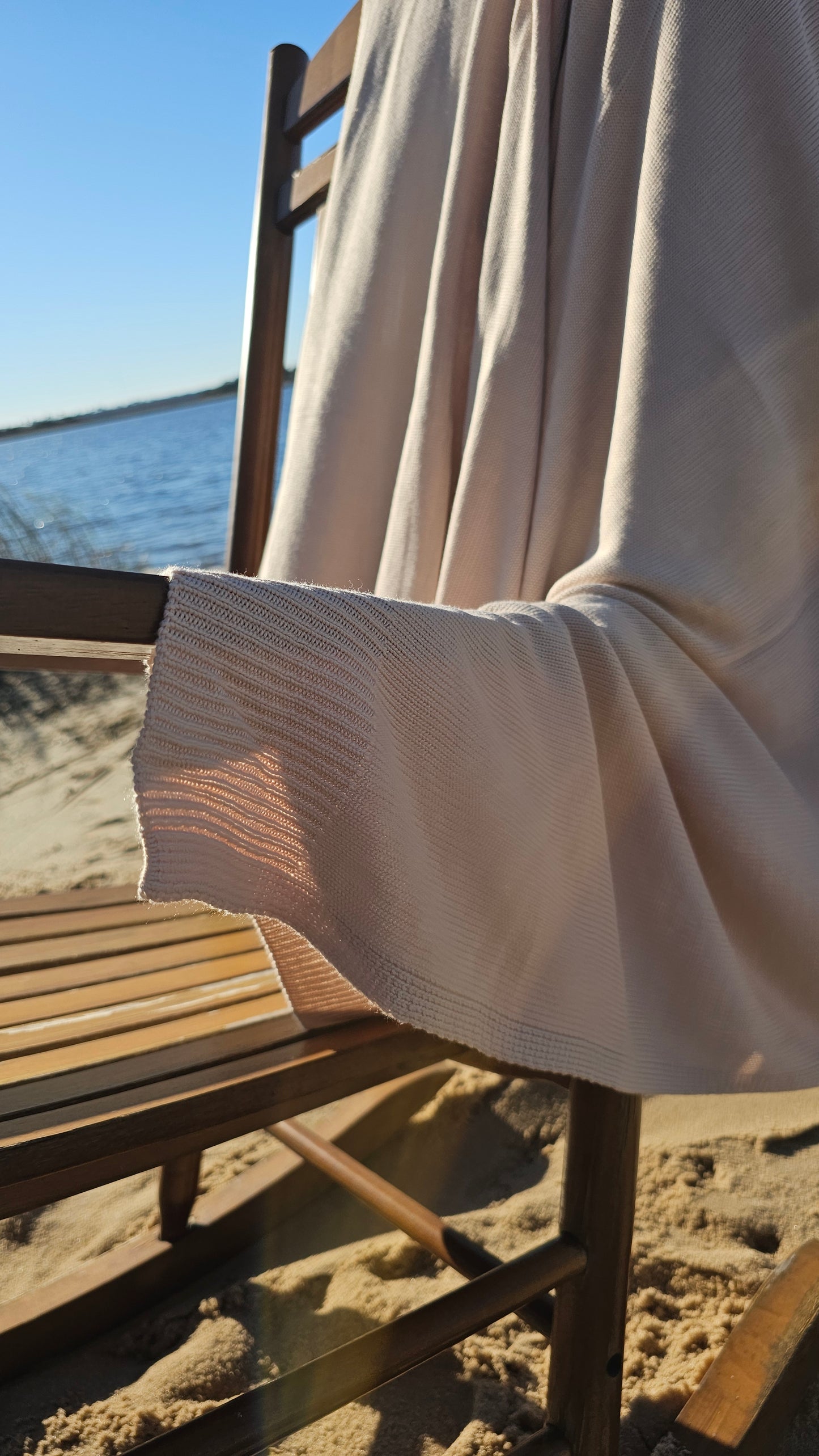 The drift throw in beige almond color, lightweight throw over rocking chair blowing in the beach breeze, oversized throw, travel throw, outdoor throw blanket, easy clean throw, durable bedding