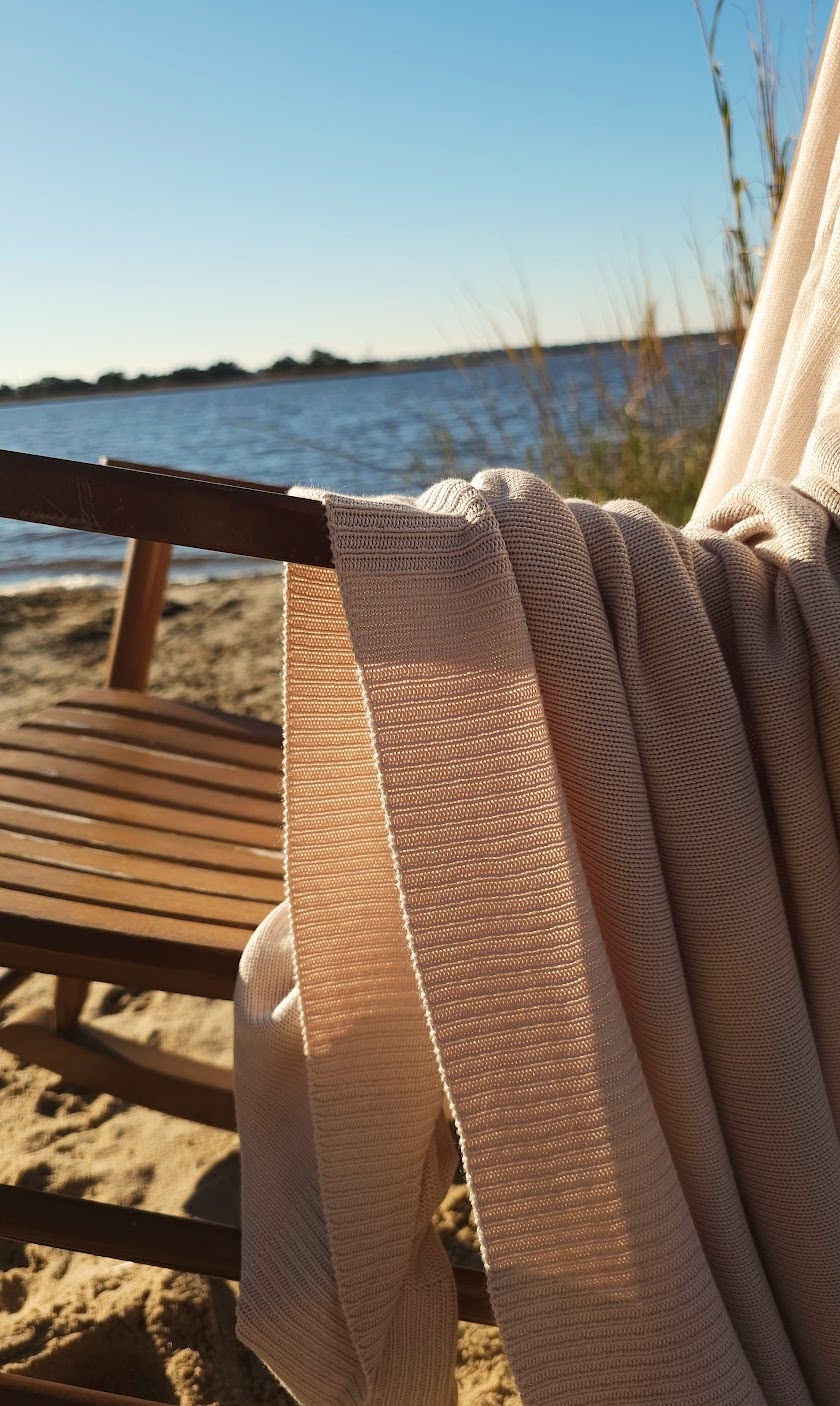 The drift throw in beige almond color, lightweight throw over rocking chair blowing in the beach breeze, oversized throw, travel throw, outdoor throw blanket, easy clean throw, durable bedding