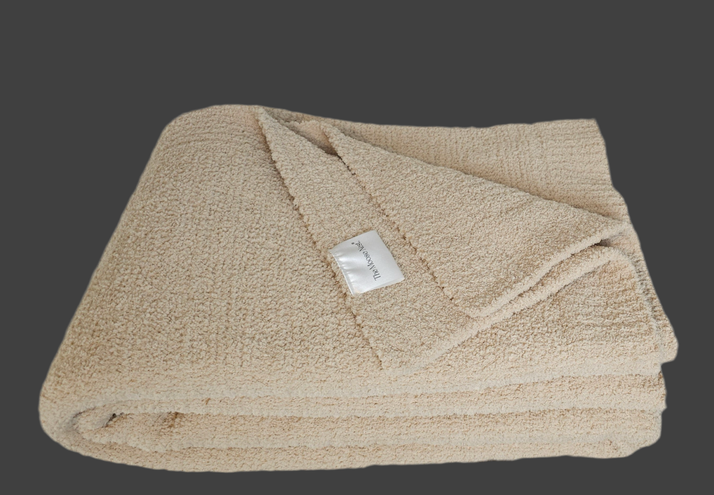 Neutral-toned Sand Nest throw folded to show it's ribbed edge and showing off its ultra-soft plush material and timeless elegance