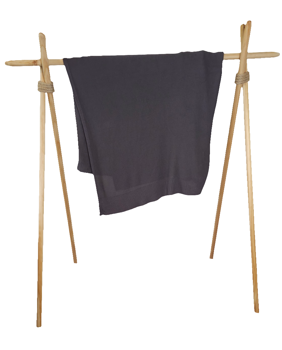 Charcoal stone colored drift throw blanket draped over modern wood rack to emphasize its lightweight yet high quality 