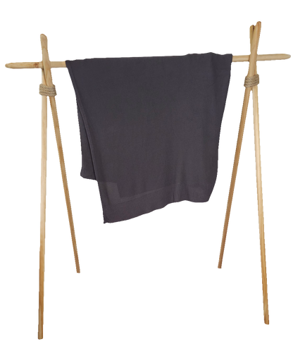 Charcoal stone colored drift throw blanket draped over modern wood rack to emphasize its lightweight yet high quality 